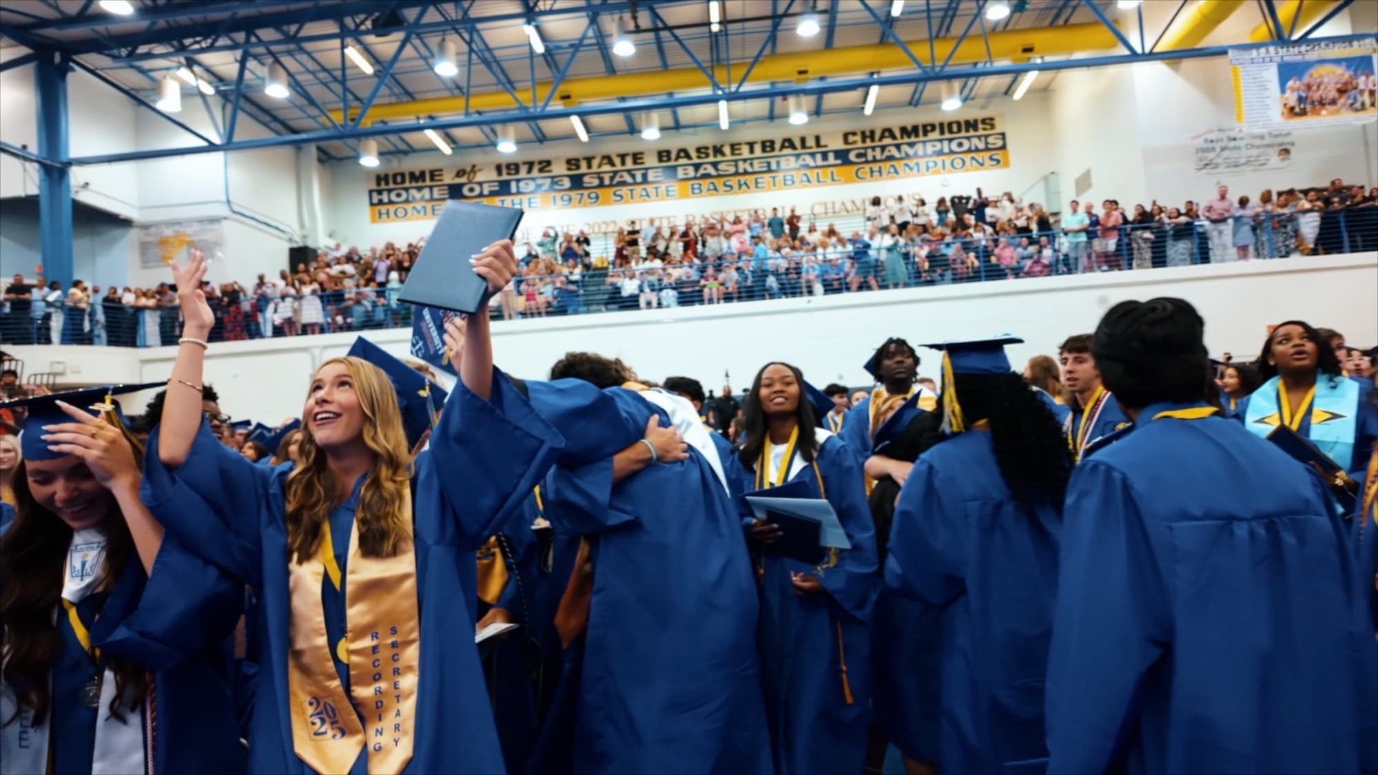Graduates celebrating beneath the gymnasium's championship banners
