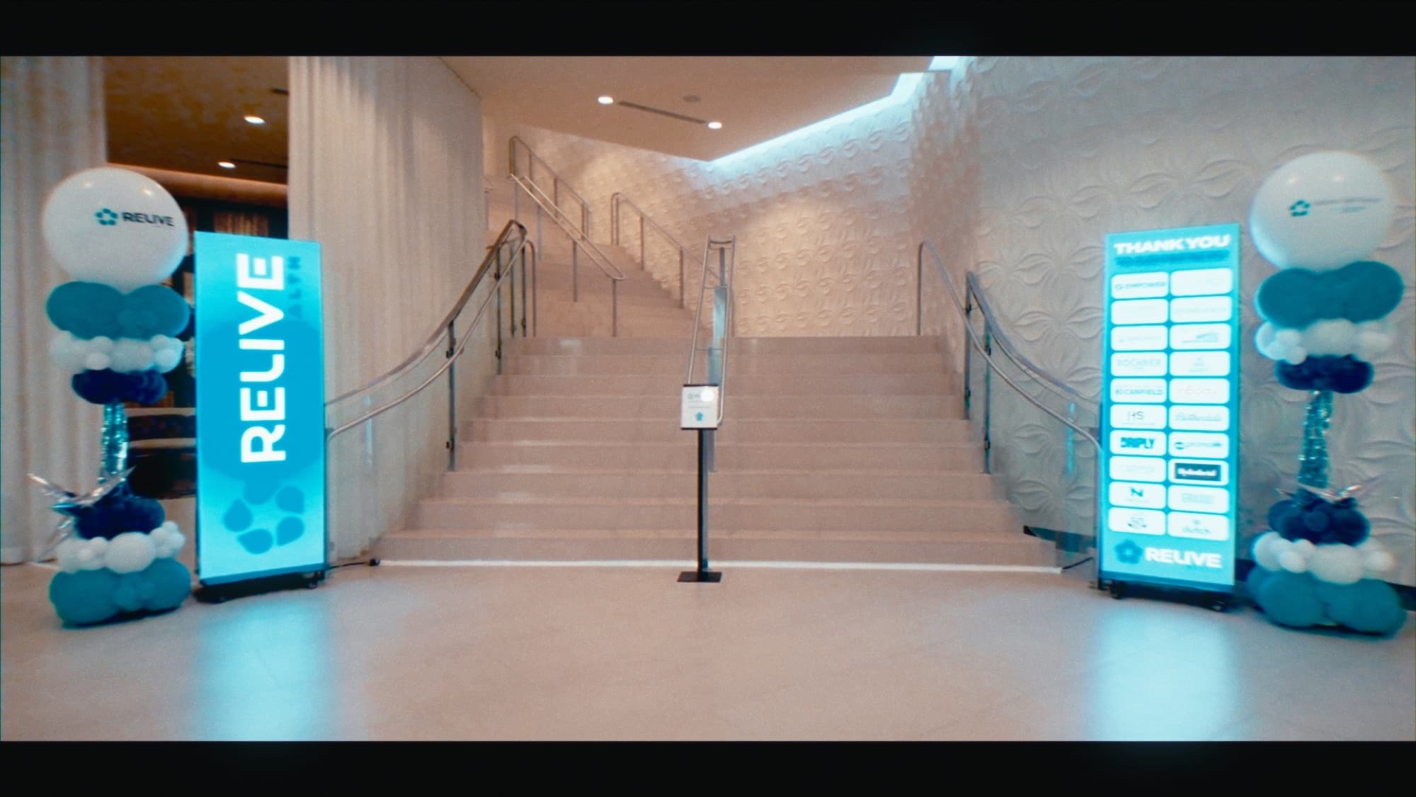 Branded Relive Health LED poster walls flanking the entrance staircase at their award show