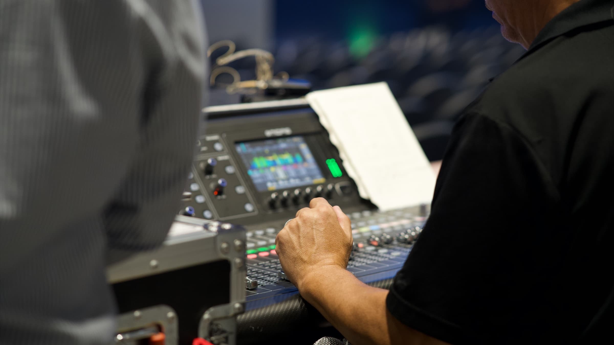 Front-of-house engineer's hands on a live audio mixing console during the SLPS kickoff event